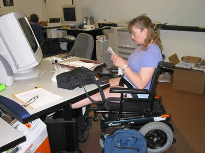 Student learning adaptive in a wheel chair at an accessible computer workstation.
