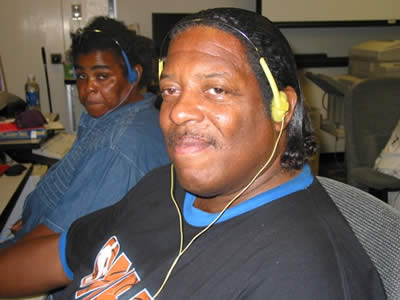 Image of student reading with a screen reader. He is looking at the camera, but concentrating on his reading.